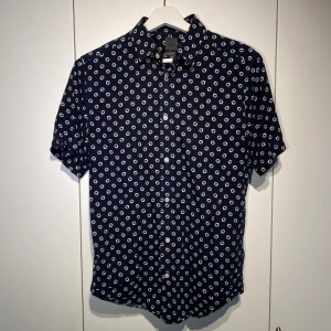H&M kortärmad mönstrad skjorta - Hej, säljer en fräsch mönstrad kortärmad skjorta från H&M i marinblått i regular fit. Storlek S och true to Size. Härligt material, bekväm & lätt att stylea. Nypris var 600kr. Pris kan diskuteras i DM. Hör av dig! 