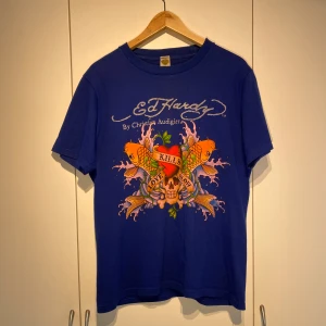 Ed Hardy T-shirt Klarblå - Hej, säljer en riktigt snygg t-shirt från Ed Hardy by Christian Audigier. Storlek L men passar M. Sparsamt använd, fint skick. Unik och utstickande. Tryck både fram & bak. Nypris 850kr. Pris kan diskuteras. Hörs i DM! 