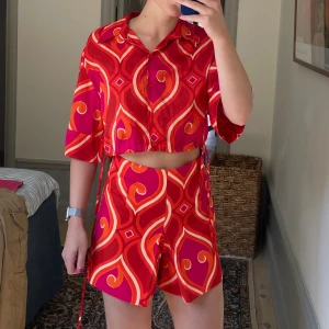 Mönstrat set från Zara - Fint mönstrat det från Zara. Toppen är skjortlikknande ganska högt croppad.  Underdelen är shorts som ser ut som en kjol. Storlek M i båda.  Finns snören man kan knyta in blusen med, där har 3 av knapparna längst ut på snörena fallit av. 