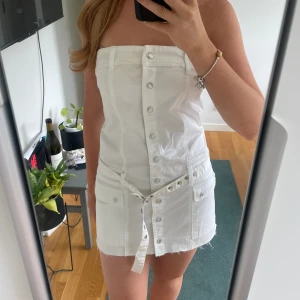 Kort klänning - Kort bandeau klänning i jeans liknande material! Super fin men för kort för mig. Köpt på plick sen innan och har en fläck fram vid bröstet (bild 1), går säkert bort i tvätten. Passar nog 160-165cm långa