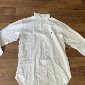 Ralph Lauren Skjorta Vit - En riktigt snygg skjorta från Ralph Lauren.Finns några små fläckar på den men är lätta att få bort med en tvätt. En av knapparna sitter lite löst även men är enkelt att fixa. Kan skicka bild på fläckarna vid intresse och priset kan sänkas vid snabb 🤑