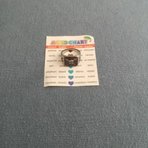 Dödskalle känslo ring - En ring som ändrar färg beroende på dina känslor (kroppsvärme). Har lite defekter då den användes förr, har tappat lite av det silvriga och minns inte om den färgar av sig eller inte... Papperet som visar vad färgen betyder ingår