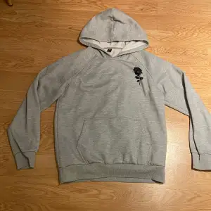 Säljer denna gråa hoodie med en svart ros på vänster sida. Använd ett fåtal gånger. 