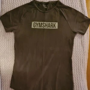 T-shirt Gymshark olivgrön använd 1 gång. - Storlek Small i nyskick då den är använd endast en gång. Säljes då den har blivit för liten. Fläckfri, djurfritt och rökfritt hem.