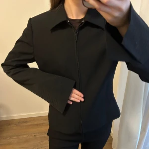 Svart jacka/overshirt - Svart jacka/overshirt i bra kvalite med små axelvaddar och tillhörande skärp. Jag har normalt storlek XS. 