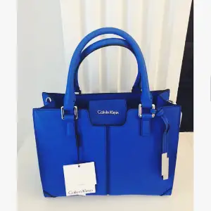 Blå väska från märket Calvin Klein. Helt felfri/knappt använd, insidan av väskan är fläckfri. Köpt i Newport california, USA i CK butik. 