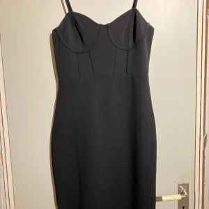 Svart lång klänning  - Svart maxi klänning i tjockare tyg från H&M. Denna klänning går ner förbi knäna och är 'form-fitting'.  Passar som finklänning men också bra att ha som vardags klädsel.