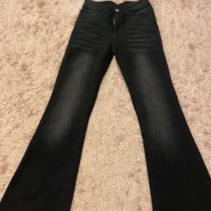 Ett par svarta bootcut jeans som är köpt från secondhand och aldrig använts