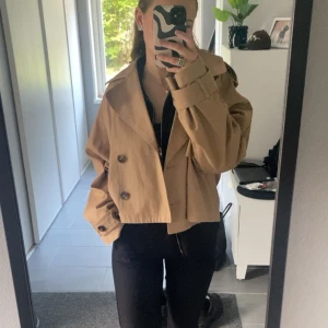 Beige short trenchcoat  - Beige short trenchcoat från Ginatricot! Slutsåld på hemsidan, nyskick!! Storlek L men passar bra på mig som brukar ha S💕