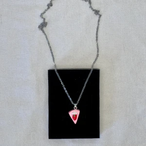 Rosa Jordgubbstårtbit Halsband  - Nyskick. Handgjort smycke. Längd: 46 cm. Tårta: 1.25 x 2 cm. Kan mötas upp i Örebro! Gulligt rosa halsband, perfekt som present 🎁 