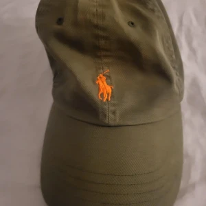 Ralph Lauren keps - En snygg och trendig keps ifrån Ralph Lauren. Kepsen är I väldigt bra skick och inga hål/missfärgningar förekommer. Kepsen går att justera så den ska passa dem flesta.