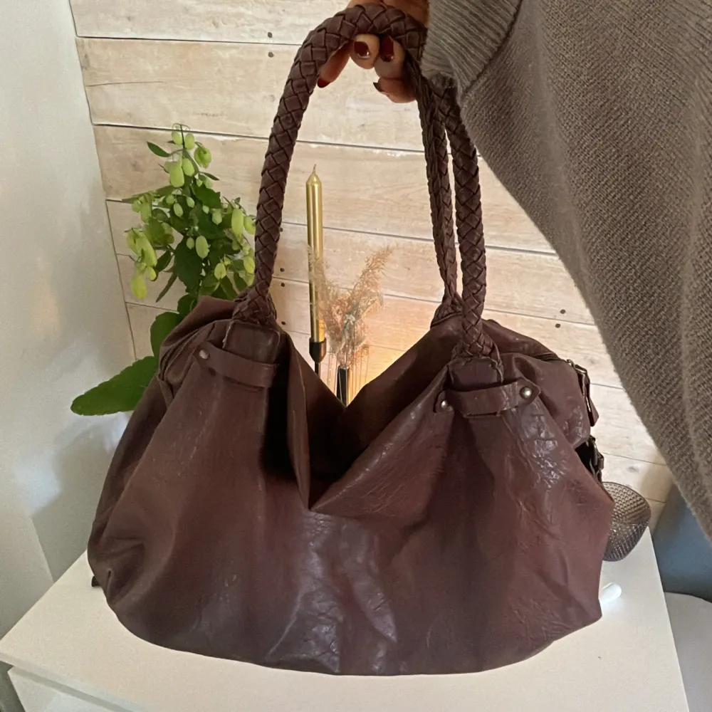 Säljer denna helt otroligt fina bruna väska med fina detaljer som banden, syns på bild två! Så fin nu tills i sommar, rymlig och får plats med dator🤩. Väskor.