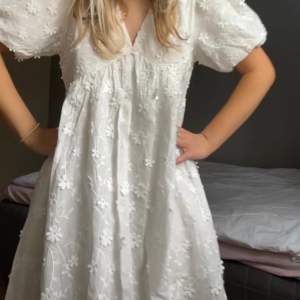 Helt oanvänd (prislappen kvar)! Så fin vit klänning med blommor köpt på danska hemsidan Bystenholt för ca 350 kr på rea, finns ej att köpa där längre dock. Storlek S men rätt pösig i modellen så passar nog även M!