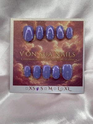 Sumire (S);ExtraShortOval  - Set handgjorda press-on naglar i en snygg lila färg pärlemorskimmrande färg med lila prickar. Naglarna har en extra kort oval form och en glansig finish som ger en trendig look. Perfekt för dig som vill ha unika naglar utan att gå till salong.S: 15 mm, 11,5 mm, 12 mm, 11 mm, 9 mm 