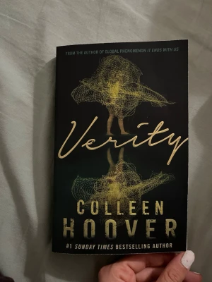 Verity av Colleen Hoover - En spännande thrillerbok med svart omslag och gul text, skriven av Colleen Hoover. Omslaget har ett konstnärligt motiv i gult och grönt som föreställer en abstrakt figur. Perfekt för dig som gillar psykologiska romaner och oväntade vändningar.