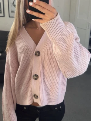 Ljusrosa ribbad kofta med stora knappar - Superfin ljusrosa kofta med bred ribbstickning och oversized passform. Koftan har stora, marmorerade knappar framtill och djup V-ringning. Perfekt att slänga över en topp för en chill look. Materialet känns mjukt och mysigt. OBS!! Storlek M men sitter bra på mig som egentligen bär XS/S!!