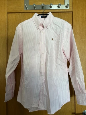 Ralph lauren skjorta  - Säljer denna ursnygga Ralph lauren skjorta. Den är randig i färgerna vit & rosa. Skjortan är helt ny och prislapp medföljer. Vid frågor hör av dig!🫂