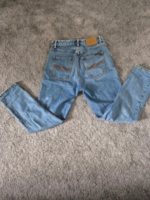 Ljusblå raka jeans med hög midja. Pria kan diskuteras - Säljer ett par ljusblå jeans med raka ben och hög midja. Jeansen har klassiska bakfickor med dekorativa sömmar och en patch bak i midjan. Tillverkade i denim med en avslappnad passform, perfekta för en trendig vardagslook.