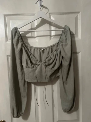 Ljusgrön croppad topp från Only - Trendig ljusgrön croppad topp från Only med långa puffärmar och snygg snörning framtill. Toppen har en mjuk struktur och bred urringning som ger en feminin vibe. Perfekt att styla med höga jeans eller kjol.