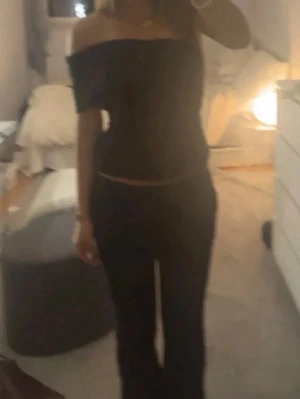 Svart offshoulder tubtopp - Snygg svart offshoulder tubtopp som sitter tight och framhäver axlarna. Perfekt till både jeans och kjol för en trendig look. Enkel och stilren design utan synliga detaljer.