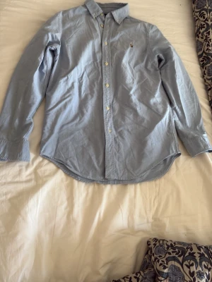 Ralph lauren skjorta - Säljer en ljusblå ralph lauren skjorta med klassisk krage och knappar framtill.  Tillverkad i bomull. Storlek: 16 år/ XS-S, custom fit 