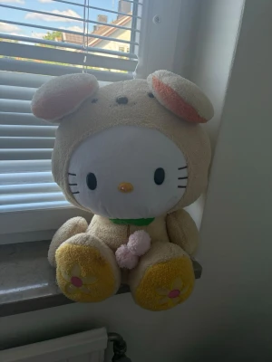 Stor Hello Kitty kanin-gosedjur - Säljer ett gulligt och stort Hello Kitty gosedjur utklädd till beige kanin med rosa och gula detaljer. Ansiktet är vitt med svarta ögon och morrhår, och tassarna har blommor. Perfekt som dekoration eller mysig present. 💗☺️ kan skicka mått I Dm ☺️