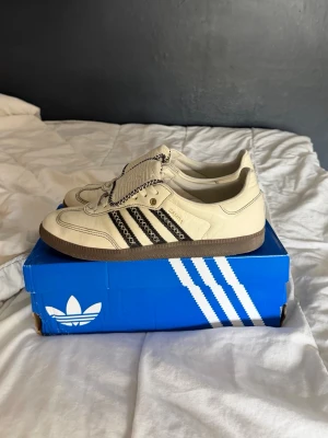 Adidas beige sneakers med svarta ränder - Säljer ett par beige Adidas sneakers med klassiska svarta ränder och unika detaljer i kontrastsömmar. Skorna har en låg silhuett och brun sula. Perfekta för dig som gillar retrovibbar och streetstyle. Köpta för 1900 så otroligt bra pris för knappt använda skor! Kvitto finns om du kommer privat! Fraktar samma dag! 