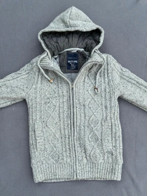 Kabelstickad cardigan  - Riktigt snygg grå mönsterstickad cardigan med foder, perfekt nu mot hösten. Storlek S. Fint skick.