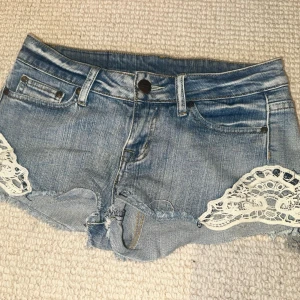 Ljusblå jeansshorts med spetsdetaljer - Snygga ljusblå jeansshorts med råa kanter och vita spetsdetaljer på sidorna. Köpte second hand i Spanien!!   Skriv gärna vid frågor och vid intresse!!🤗