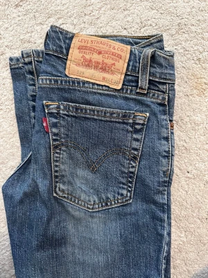 Levi's 529 blå jeans - Ett par klassiska blå Levi's 529 jeans som är bootcut och har snygga slitningar. Jeansen har fem fickor, Levi's ikoniska röda etikett på bakfickan och detaljerade sömmar. Tillverkade i slitstark denim som passar perfekt till en avslappnad stil.