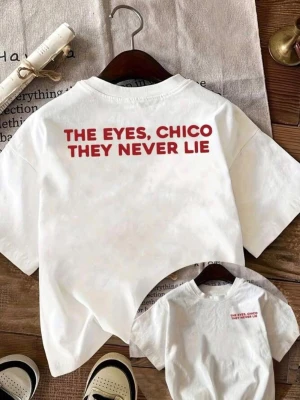 Vit t-shirt med röd text - Vit t-shirt med trycket 'THE EYES, CHICO THEY NEVER LIE' i rött på ryggen och mindre text framtill. Klassisk passform och rund halsringning, perfekt för en avslappnad stil.