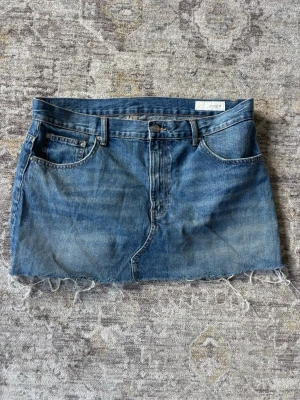 Blå jeanskjol med rå kant - Kort blå jeanskjol från Zara. Knappt använd 