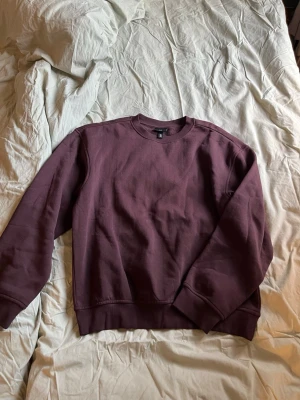 Vinröd loose fit sweatshirt H&M - Säljer en vinröd sweatshirt från H&M i loose fit-modell. Tröjan har rund halsringning, ribbade muddar vid ärmslut och nederkant samt är gjord i mjukt bomullsmaterial. Perfekt för en chill och avslappnad stil.
