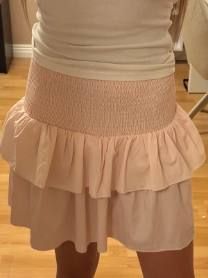 Ljusrosa volangkjol - Ljusrosa kortkjol med dubbla volanger från Gina Tricot. Kjolen är gjord i ett tunt, flowy material som ger en luftig känsla. 