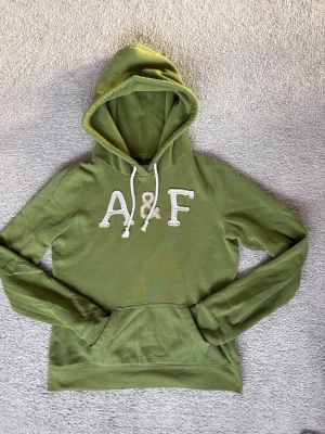 Abercrombie & Fitch Hoodie olivgrön  - Säljer en olivgrön Abercrombie & Fitch Hoodie i fint skick. Hör av dig vid frågor. 
