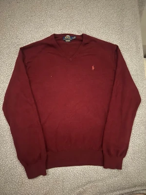 Vinröd V-ringad tröja Polo Ralph Lauren - Vinröd V-ringad tröja från Polo Ralph Lauren i 100% bomull. Fint skick.