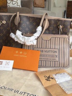  Monogram handväska - Snygg handväska i klassiskt brunt monogrammönster med beige detaljer. Väskan har två långa handtag och en avtagbar innerficka med randigt mönster och tryck. Tillbehör som dustbag och certifikat medföljer.