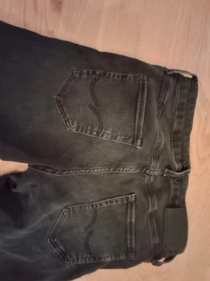 Svarta slim fit jeans - Säljer ett par svarta jeans med raka ben och klassiska bakfickor med dekorativ söm. Jeansen har bälteshällor och en svart patch bak i midjan. Perfekta till en avslappnad stil och passar till det mesta. 28w 30L