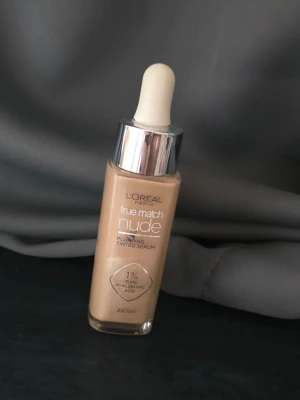 True Match Nude Foundation Light - L'Oréal Paris True Match Nude Plumping Tinted Serum i nyansen 2-3 Light. Flytande foundation med pipettapplikator och silvrigt lock. Innehåller 1% hyaluronsyra för återfuktande effekt och ger en naturlig, fräsch finish. Använd några gånger 