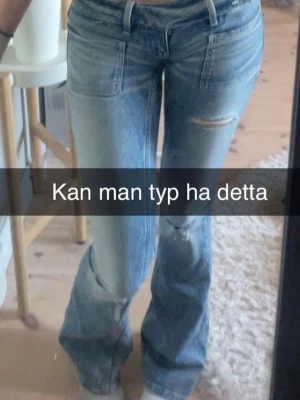 Ljusblå slitna bootcut jeans - Säljer ett par ljusblå jeans med bootcut passform och slitningar på låren och knäna. Jeansen har klassiska fickor fram och bak samt hällor för skärp. Perfekta för en avslappnad och trendig look. Storlek XS Tall. 