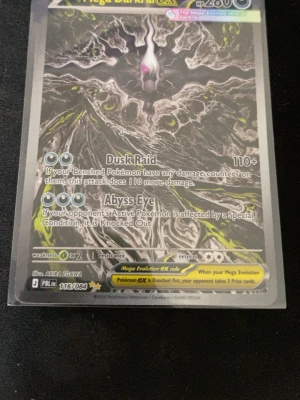 Pokémonkort Mega Darkrai EX - Säljer ett Pokémonkort Mega Darkrai EX med coolt mörkt motiv och holografiska detaljer. Kortet har attacker som Dusk Raid och Abyss Eye. Kortet är svart, grått och har inslag av gult och lila. Perfekt för samlare eller dig som vill boosta din lek.