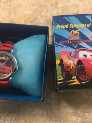 Röd Cars klocka med Presentlåda  - Säljer en cool röd klocka med motiv av Lightning McQueen .  Klockan har ett runt ur med tydliga siffror och en röd rem. Perfekt för dig som gillar bilar och vill ha en unik accessoar! Nya klocka med nya batterier 