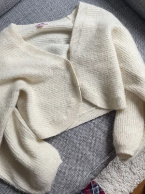 Stickad kofta Gina tricot - Säljer en jättesöt stickad kofta/bolero från Gina tricot. Färgen är en vanilj vit färg om ni förstår vad jag menar, en mix mellan vitt och ljus ljus beige🩷På 3e bilden syns en fläck på armen men ingenting man tänker på. Säljer då den blivit för liten. Skriv i DM om frågor! Använd fåtal gånger.