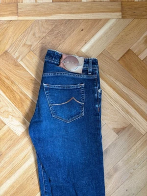 Blå raka jeans från Jacob Cohen - Snygga blå jeans från Jacob Cohen med raka ben och klassisk femficksmodell. Jeansen har kontrastsömmar och en läderpatch med logga bak i midjan. Tillverkade i mjukt denimtyg som ger en skön passform och tidlös look.