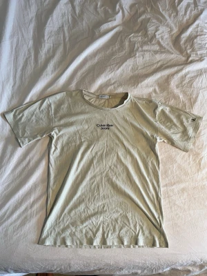 Calvin Klein (Herr) - Beige T-shirt från Calvin Klein (Herr x/s, pojke 14 år). Defekter förekommer på bilderna