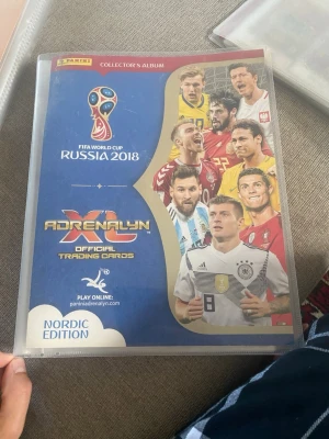 Panini VM 2018 samlaralbum + kort - Säljer ett Panini Adrenalyn XL samlaralbum från FIFA World Cup Russia 2018, Nordic Edition. Albumet innehåller officiella trading cards med fotbollsspelare, bland annat från FC Barcelona. Perfekt för dig som gillar fotboll och samlarkort.