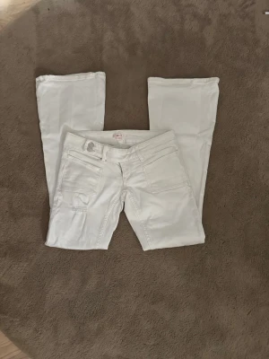 Vita bootcut jeans med slitningar - Säljer ett par vita bootcut jeans i storlek s från Gina tricot. Jeansen är sparsamt andvända och har inga defekter. Jeansen har en snygg design på bakfickorna samt hål vid knäna.