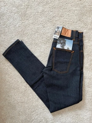 Mörkblå jeans från Nudie Jeans - Säljer att par väldigt snygga Nudie Jeans som är NYA i modellen Grim Tim! ——————————————————————————                                                          📐| Storlek: 28-32                                                  Märke: Nudie jeans      (Selvedge)                                       Skick: Nytt skick  (använd 1 gång -lappen är av)          💵| Ny Pris: 1699kr                                                   ✍🏻| Skriv om du har några frågor