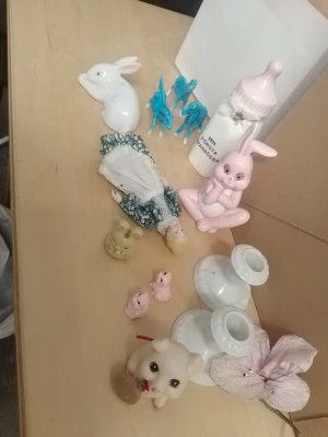 Samling porslinsfigurer djur & prydnader - Säljer en mixad samling porslinsfigurer och prydnader, bland annat kaniner, grisar, en docka i klänning, två vita ljusstakar och en rosa nappflaska. Figurerna är i olika färger som rosa, vitt, blått och beige. Perfekt för dig som gillar söta dekorationer och samlarprylar.