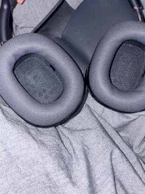 Svarta over-ear hörlurar - Snygga svarta over-ear hörlurar med mjuka, ovala öronkuddar i tyg och ett robust huvudband. Yttersidan är matt och stilren, perfekt för dig som vill ha bra ljud och komfort under längre lyssningssessioner.